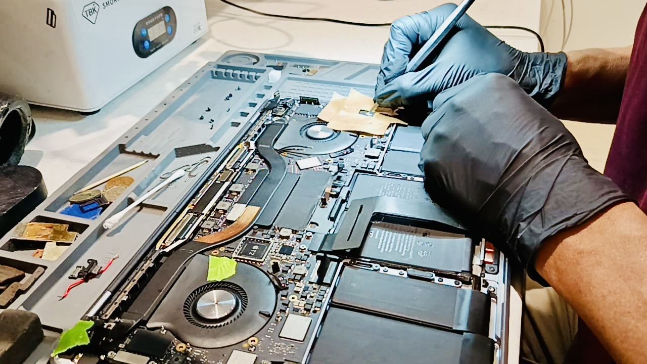 Technician performing precision MacBook logic board repair at iDevice Repair Lab