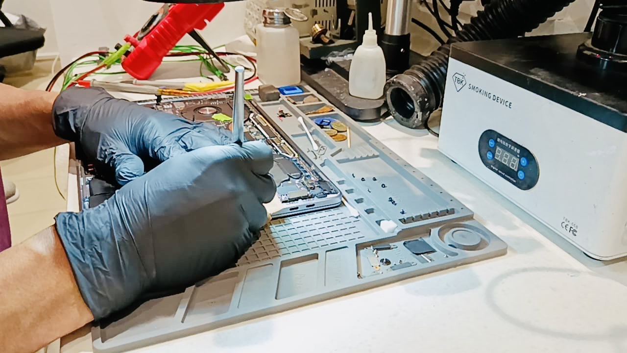 Technician performing precision micro-soldering at iDevice Repair Lab workbench